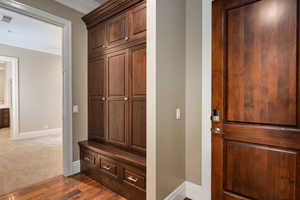 Mudroom with baseboards, dark wood-style floors, visible vents, and crown molding