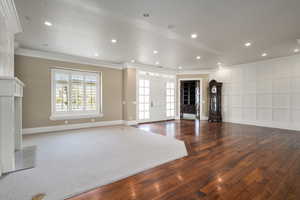 Unfurnished living room with hardwood / wood-style flooring, baseboards, crown molding, and recessed lighting