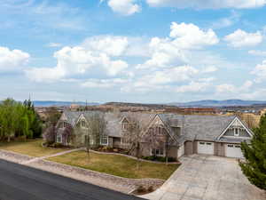 View of front of property featuring a garage, a mountain view, concrete driveway, and a front yard