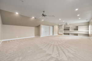 Additional living space featuring a ceiling fan, light colored carpet, vaulted ceiling, and baseboards