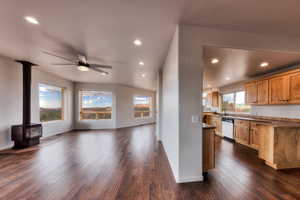 Kitchen with recessed lighting, dark wood-style floors, open floor plan, dishwasher, and a wood stove