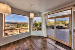 Unfurnished dining area with dark wood-style flooring, visible vents, and baseboards