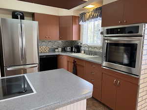 Kitchen featuring black appliances, tasteful backsplash, a sink, and light countertops