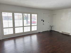 Spare room with dark wood-style flooring, visible vents, and a textured ceiling