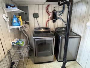 Washroom featuring laundry area, separate washer and dryer, and wood walls