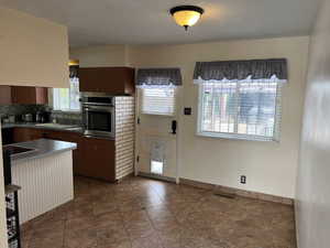 Kitchen featuring visible vents, decorative backsplash, a sink, oven, and baseboards