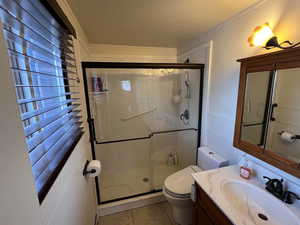 Bathroom with vanity, a shower stall, toilet, and tile patterned floors