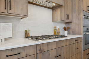 Kitchen with custom exhaust hood, tasteful backsplash, light countertops, and stainless steel gas cooktop