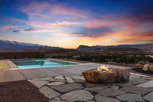 View of swimming pool with an outdoor fire pit, a mountain view, a fenced backyard, and a patio