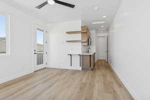 Unfurnished living room with light wood-style floors, a ceiling fan, healthy amount of natural light, and recessed lighting