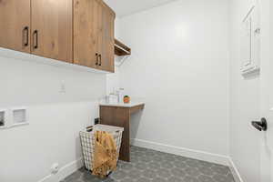 Laundry room with dark floors, cabinet space, and washer hookup