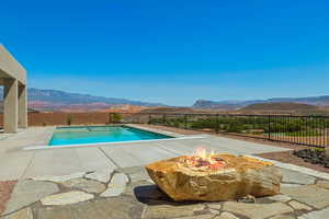 View of pool featuring a mountain view, an outdoor fire pit, a fenced backyard, and a patio area