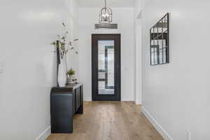 Foyer entrance with light wood finished floors and a chandelier