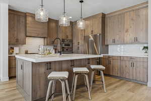 Kitchen featuring light wood-style floors, decorative backsplash, light countertops, and a textured ceiling