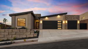 Contemporary home with a garage, concrete driveway, stone siding, and stucco siding