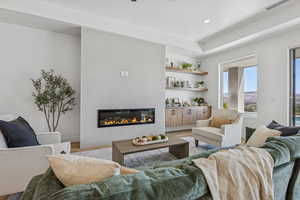 Living area with wood finished floors, a tiled fireplace, and recessed lighting