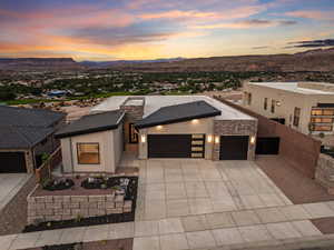 Contemporary house with a mountain view, an attached garage, stone siding, and concrete driveway