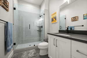 Full bath featuring vanity, a shower stall, toilet, and tile patterned floors