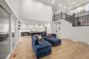 Living room with visible vents, light wood-style flooring, and a towering ceiling