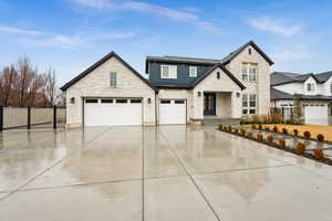 View of front of property featuring a garage, fence, and driveway