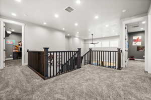 Corridor with recessed lighting, carpet, visible vents, and an upstairs landing