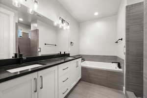 Bathroom featuring double vanity, a sink, a tile shower, and a bath