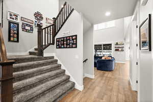 Stairway with a high ceiling, plenty of natural light, wood finished floors, and baseboards