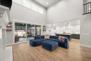 Living area with baseboards, a towering ceiling, and light wood-style floors