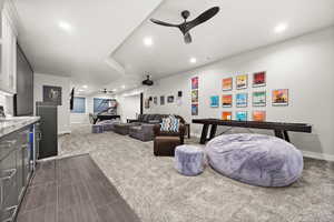 Living area featuring recessed lighting, dark carpet, baseboards, and ceiling fan