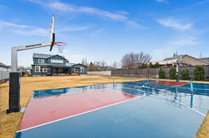 View of sport court with community basketball court, fence, and a yard