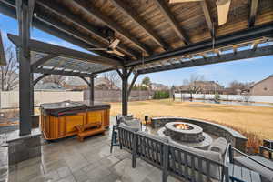 View of patio featuring a hot tub, a fenced backyard, a fire pit, and ceiling fan