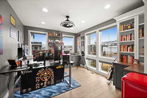 Office area with ceiling fan, light wood finished floors, visible vents, and recessed lighting