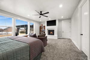 Carpeted bedroom with baseboards, a glass covered fireplace, a ceiling fan, and recessed lighting