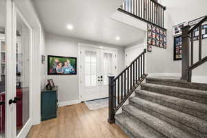 Entryway with light wood finished floors, baseboards, stairway, french doors, and recessed lighting