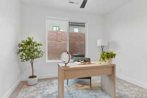 Carpeted home office featuring ceiling fan and baseboards