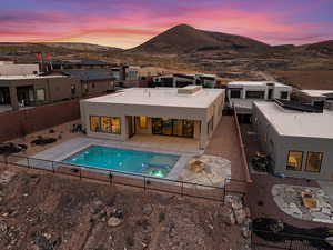 Back of house at dusk featuring a fenced backyard, stucco siding, a mountain view, and a patio area