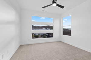Spare room featuring plenty of natural light, carpet floors, and a ceiling fan