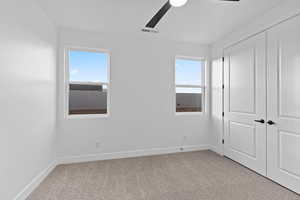 Unfurnished bedroom with light colored carpet, multiple windows, and a closet