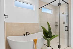 Full bath with tile walls, a stall shower, and a freestanding tub