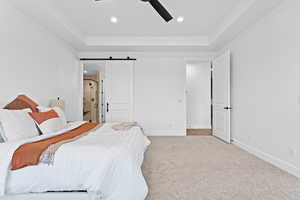 Carpeted bedroom with a raised ceiling, recessed lighting, a barn door, and ceiling fan