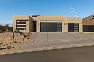 View of front facade with stucco siding, a garage, and concrete driveway