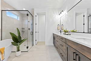 Bathroom featuring double vanity, a freestanding bath, a shower stall, and tile patterned floors