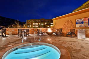 Pool at twilight featuring a fire pit, a patio area, and a hot tub