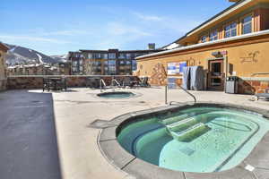 View of swimming pool featuring a hot tub, a mountain view, and a patio