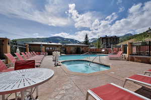 Pool featuring a patio area, fence, a mountain view, and a community hot tub