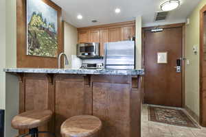 Kitchen featuring stainless steel appliances, visible vents, a sink, and a kitchen breakfast bar