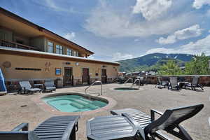 View of swimming pool with a patio area, a mountain view, and a community hot tub