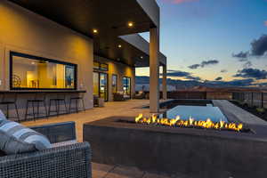 View of patio / terrace with outdoor dry bar, an outdoor living space with a fire pit, fence, and a mountain view