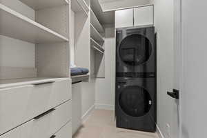 Walk in closet with stacked washer / drying machine and light tile patterned floors