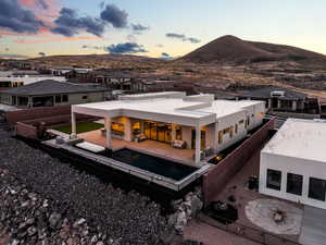 Back of property at dusk with a fenced backyard, a mountain view, a residential view, a fenced in pool, and a patio area